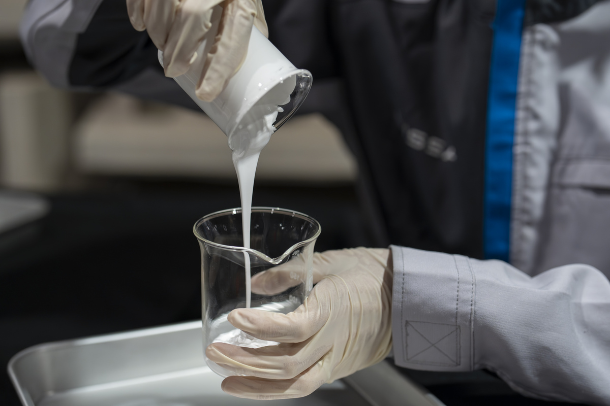 White paint being poured from one glass container to another